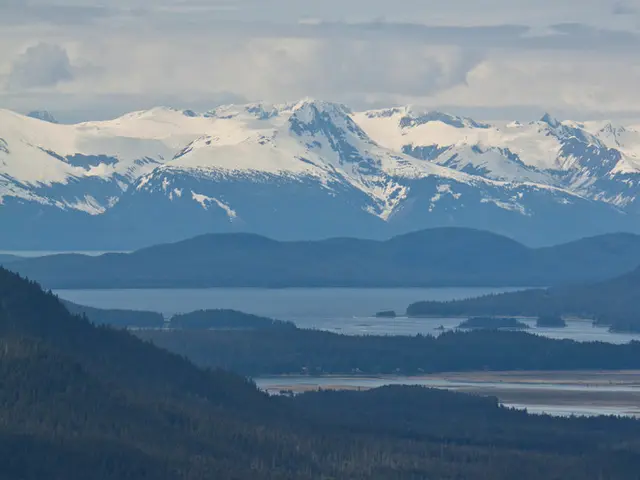 In the image there are many mountains covered with snow and there is a sea in front of those...